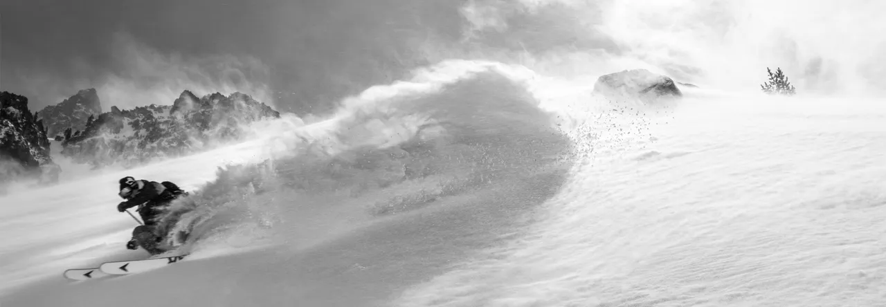 Skier in deep powder snow with mountains in the background