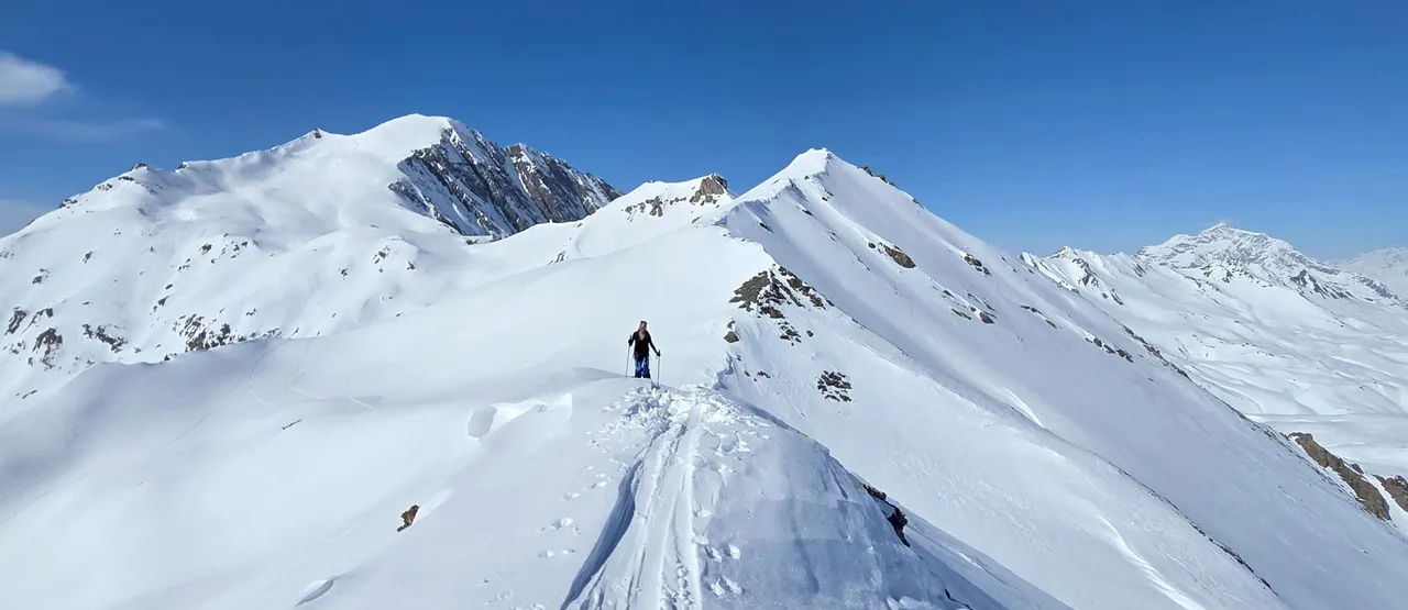 Ski tourer on a mountain ridge with vast alpine panorama