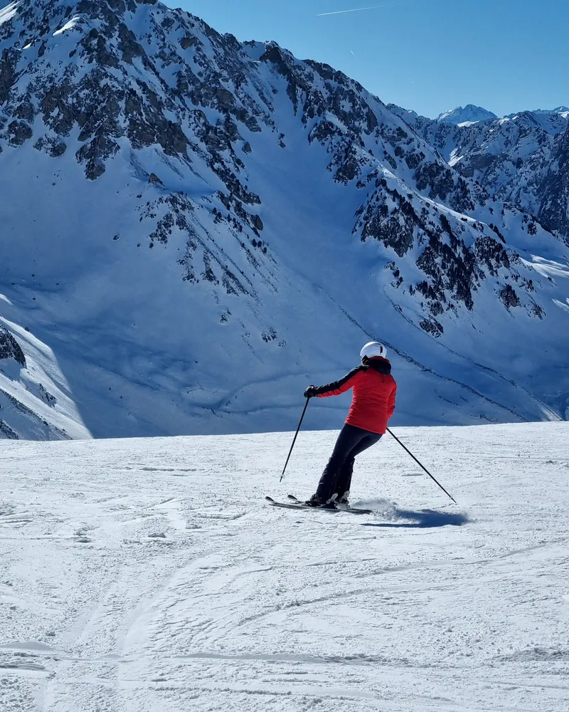 Skier carving on a sunny slope with dramatic mountain backdrop