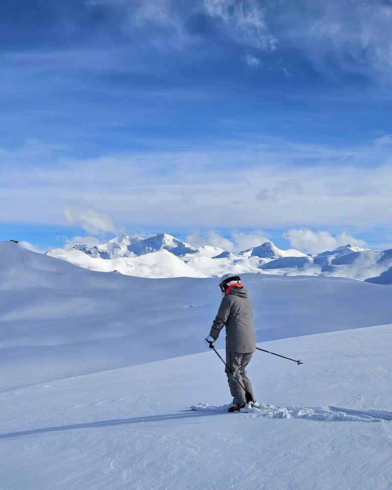 Lone skier on pristine snow with panoramic mountain views