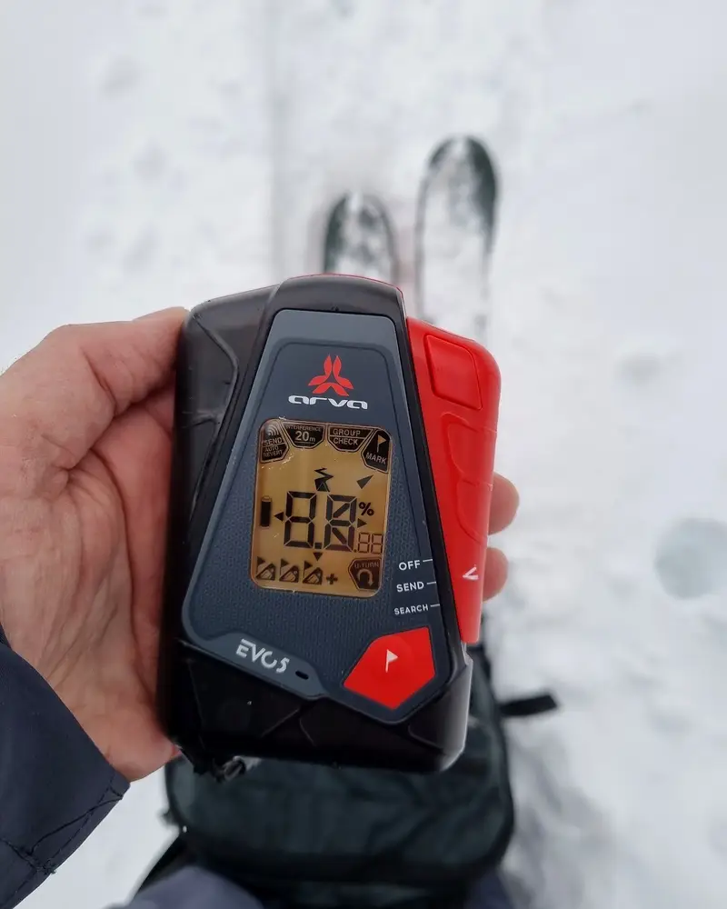 Avalanche transceiver (DVA) held in hand before an off-piste run
