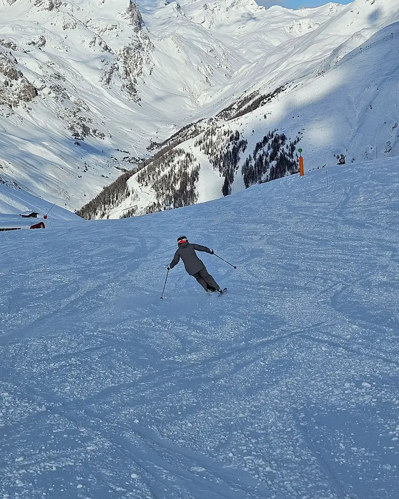 Skier carving a turn on a groomed piste above the valley