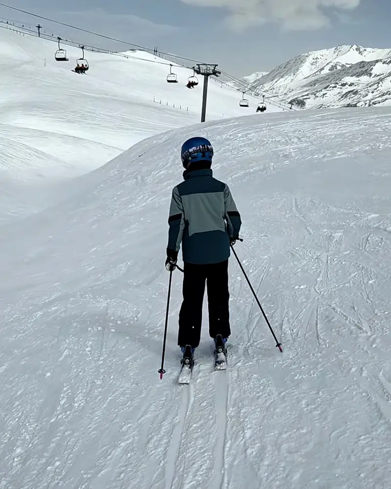 Teenage skier on a piste below a chairlift
